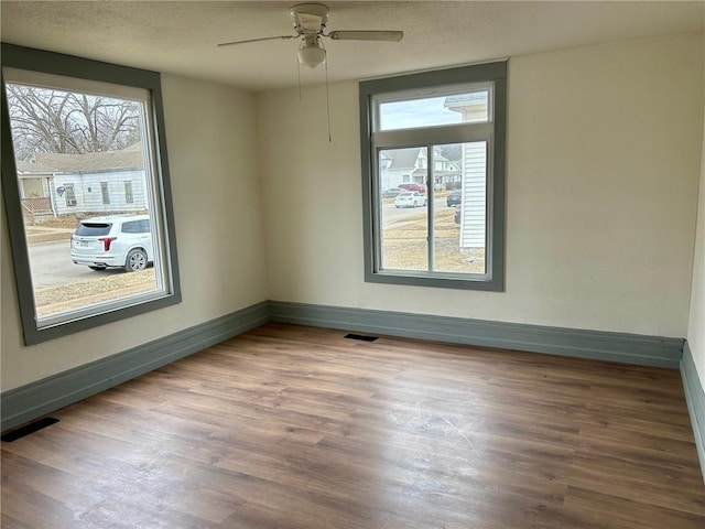 empty room featuring wood finished floors, visible vents, and baseboards