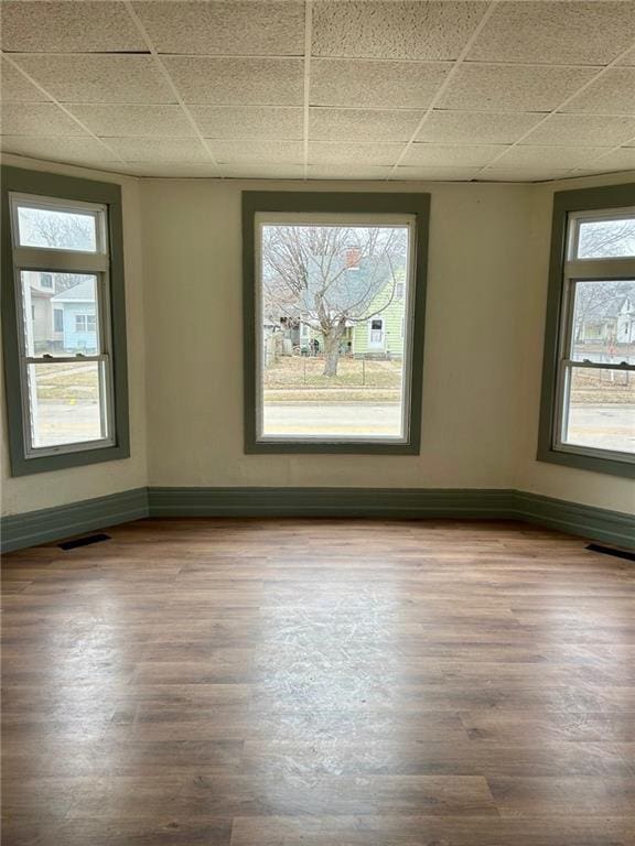 spare room featuring visible vents, baseboards, and wood finished floors