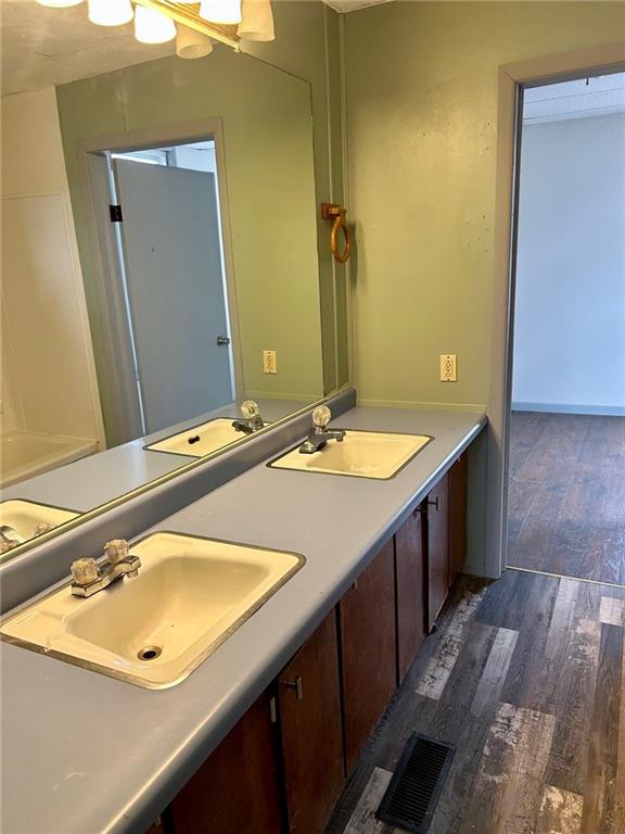 bathroom featuring double vanity, a sink, and wood finished floors