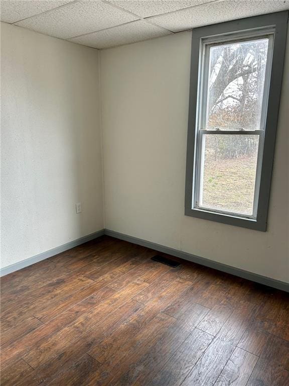 unfurnished room featuring visible vents, baseboards, a drop ceiling, and dark wood-type flooring