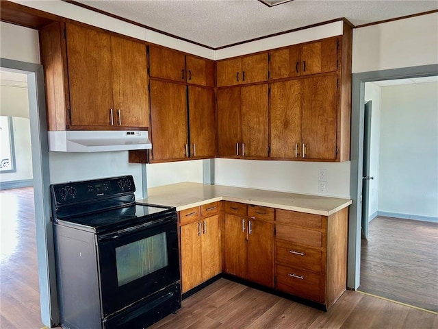 kitchen with dark wood-style floors, light countertops, electric range, a textured ceiling, and under cabinet range hood