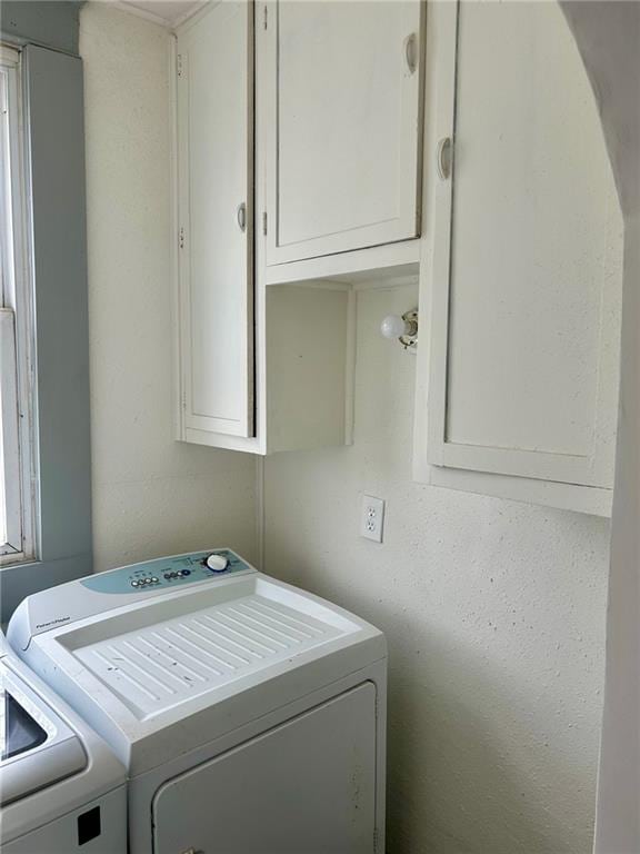 clothes washing area with separate washer and dryer and cabinet space