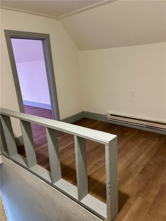 bonus room with a baseboard heating unit, vaulted ceiling, and wood finished floors