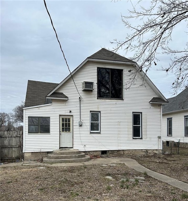 back of property featuring entry steps, a shingled roof, fence, and a wall mounted AC