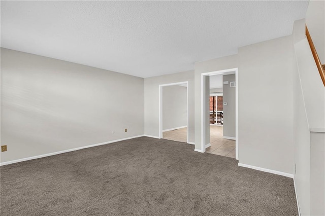 unfurnished room with a textured ceiling, carpet floors, and baseboards