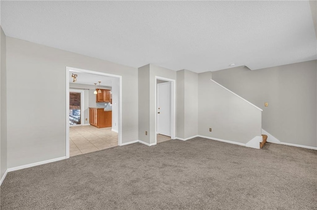 interior space with baseboards, light carpet, stairway, and a textured ceiling