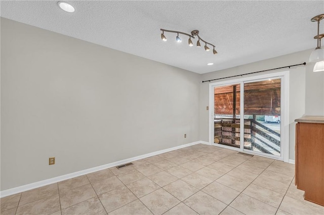 unfurnished room featuring visible vents, a textured ceiling, baseboards, and light tile patterned flooring