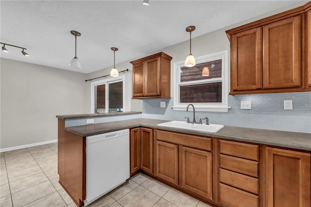 kitchen with decorative light fixtures, brown cabinets, a sink, dishwasher, and a peninsula