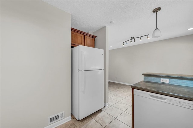 kitchen featuring white appliances, light tile patterned floors, visible vents, dark countertops, and brown cabinets