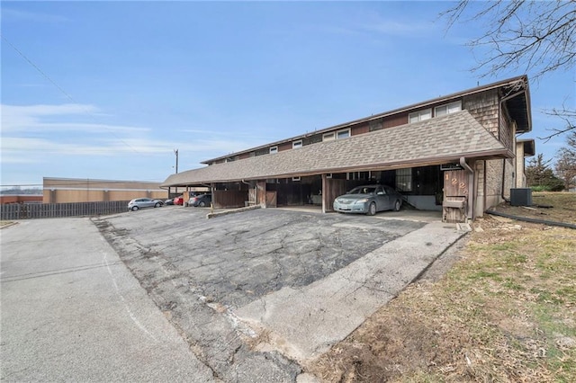 exterior space featuring a shingled roof, covered parking, and central AC