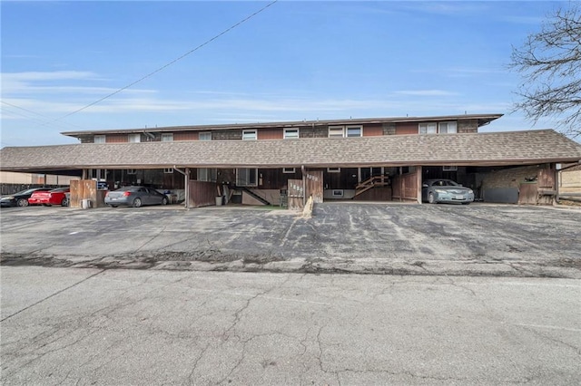 view of property with covered parking and roof with shingles