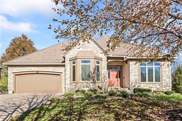 view of front of property featuring a garage, stone siding, and driveway