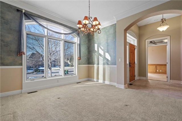 unfurnished dining area with baseboards, visible vents, arched walkways, carpet, and crown molding