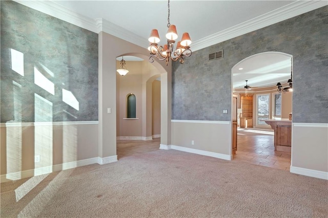 spare room with arched walkways, carpet flooring, crown molding, and visible vents