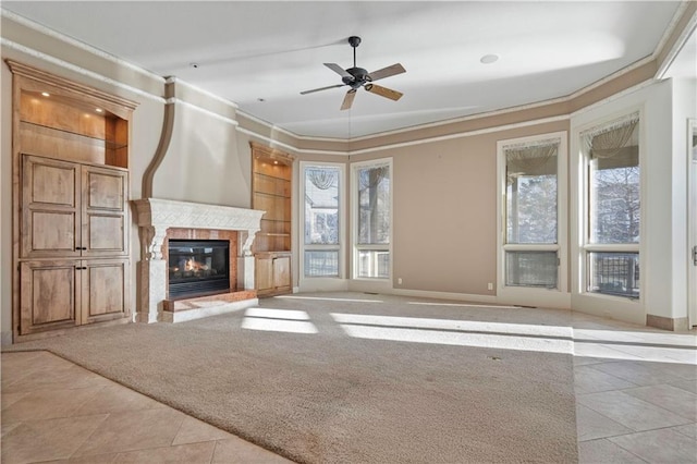 unfurnished living room with ornamental molding, carpet, a glass covered fireplace, and a wealth of natural light