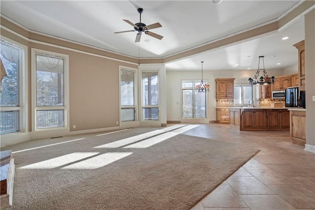 unfurnished living room with recessed lighting, baseboards, a sink, and ceiling fan with notable chandelier