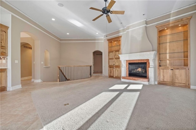 unfurnished living room featuring built in shelves, arched walkways, and crown molding