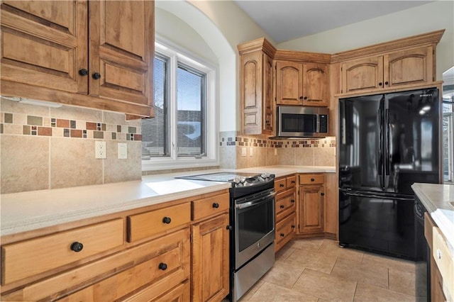 kitchen featuring black appliances, brown cabinetry, light countertops, and decorative backsplash