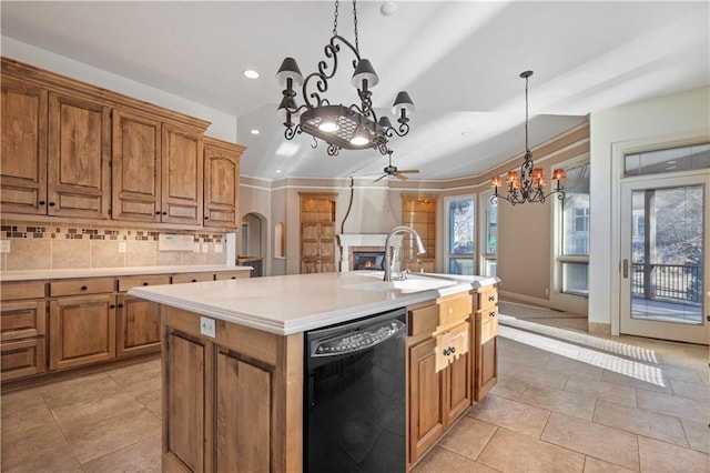 kitchen featuring light countertops, decorative backsplash, brown cabinetry, a glass covered fireplace, and dishwasher