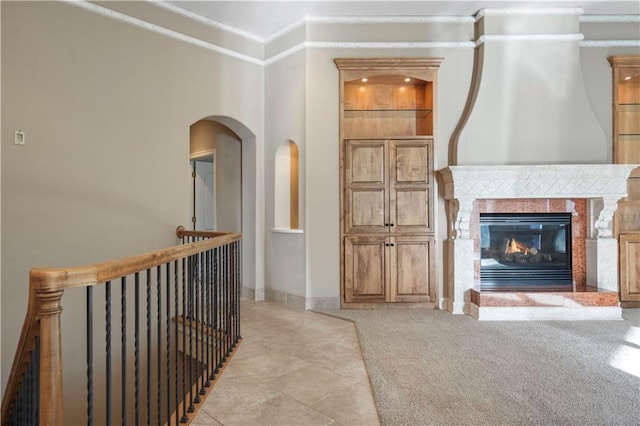 interior space featuring light carpet, a premium fireplace, baseboards, and crown molding