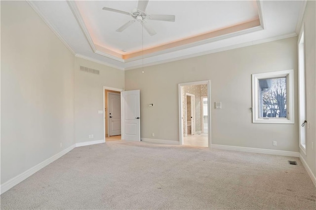 unfurnished bedroom featuring light carpet, a tray ceiling, visible vents, and baseboards