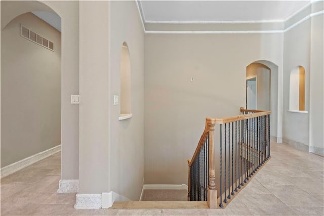 stairway featuring arched walkways, visible vents, and baseboards