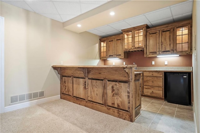 kitchen with brown cabinets, visible vents, a kitchen breakfast bar, baseboards, and fridge