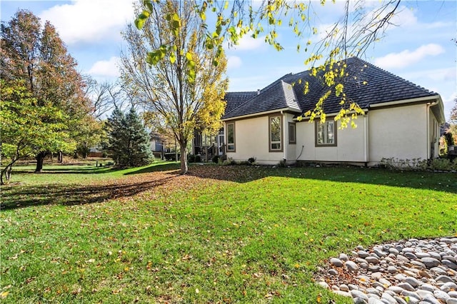 rear view of house with a lawn and stucco siding