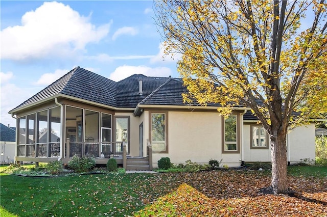 view of front of property with a front lawn, a sunroom, and stucco siding