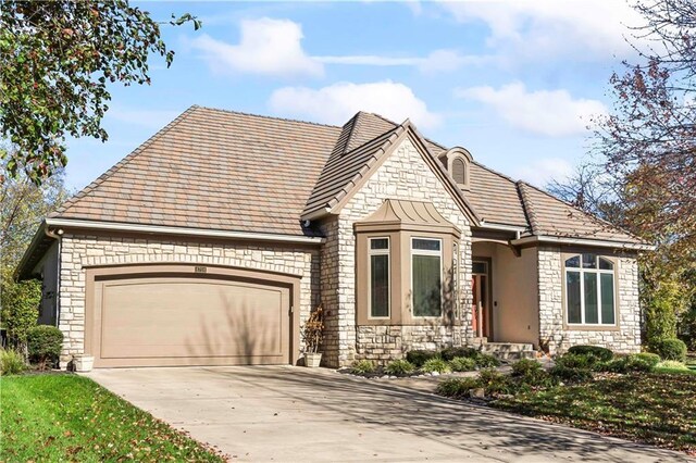 view of front of home featuring stone siding, concrete driveway, and an attached garage