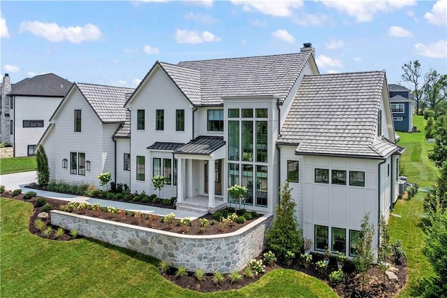 view of front of home featuring metal roof, central AC, a front lawn, a standing seam roof, and a chimney