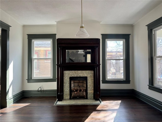 unfurnished living room with dark wood-style floors, a healthy amount of sunlight, ornamental molding, and a fireplace with flush hearth