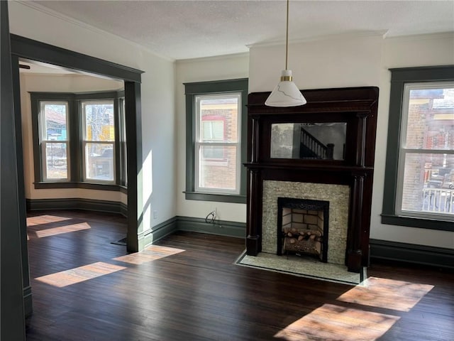 unfurnished living room with a healthy amount of sunlight, crown molding, and wood finished floors