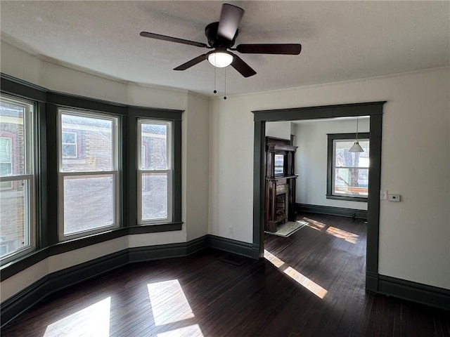 unfurnished room featuring dark wood-style floors, a fireplace with flush hearth, baseboards, and a textured ceiling