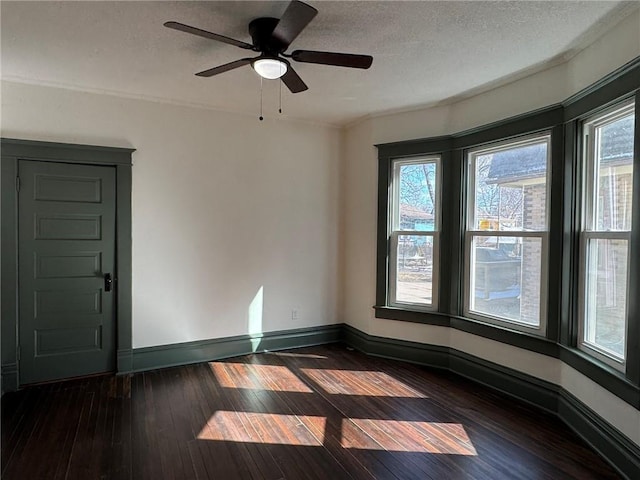 unfurnished room featuring dark wood-style floors, ceiling fan, a textured ceiling, and baseboards