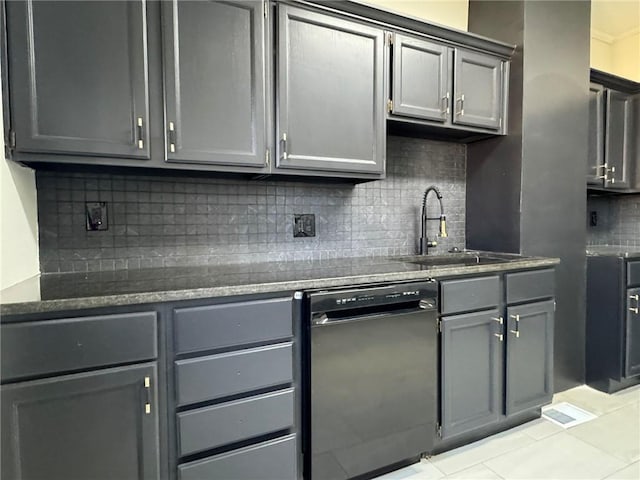 kitchen featuring a sink, black dishwasher, backsplash, gray cabinets, and dark stone counters