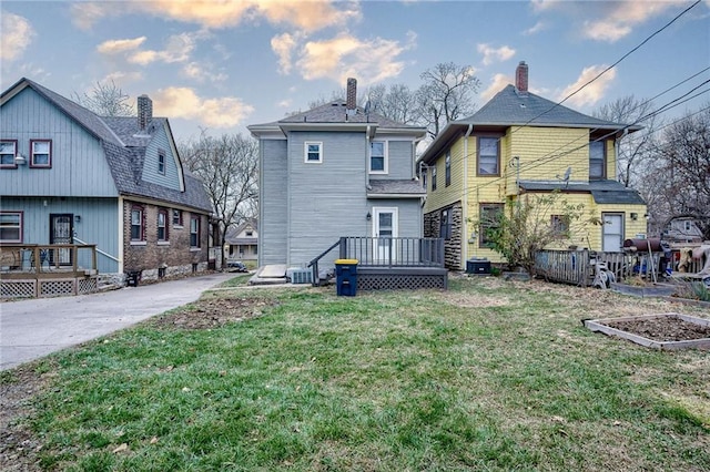 rear view of house with a lawn and a wooden deck