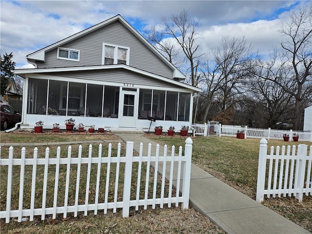 view of front of property with a fenced front yard, a front yard, and a sunroom