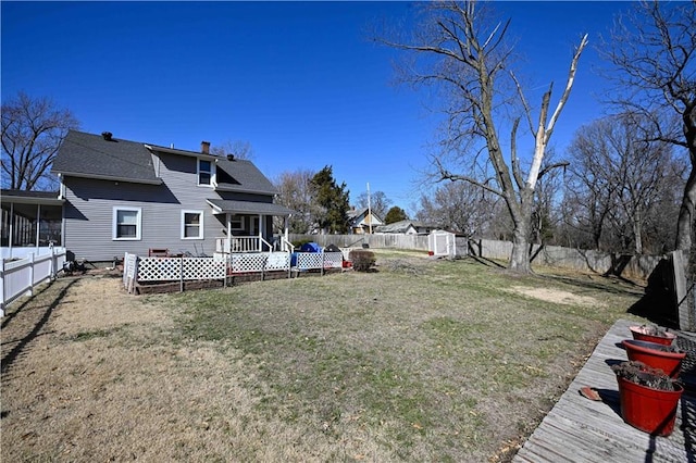 view of yard featuring an outbuilding, a fenced backyard, and a sunroom