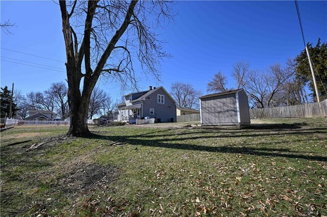 view of yard featuring a shed, an outdoor structure, and fence