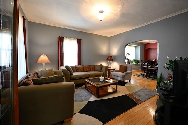 living area featuring arched walkways, ornamental molding, and hardwood / wood-style floors