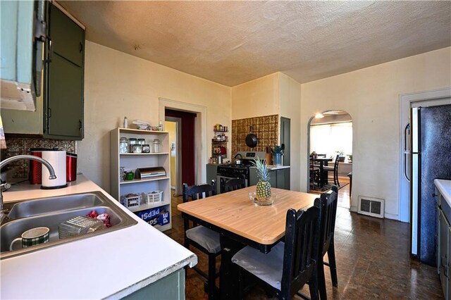 dining space featuring arched walkways, visible vents, and a textured ceiling