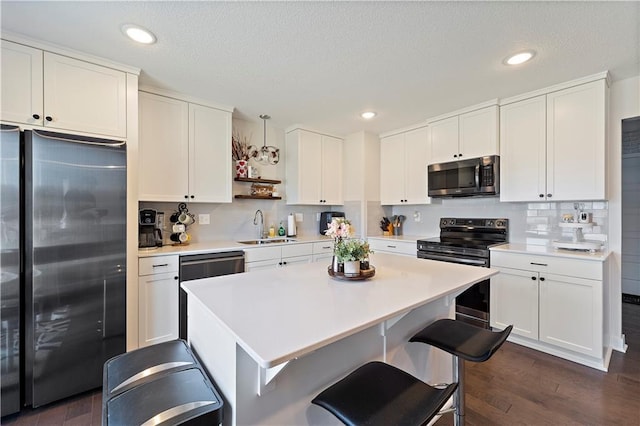 kitchen featuring dark wood-style flooring, a sink, stainless steel appliances, light countertops, and white cabinetry