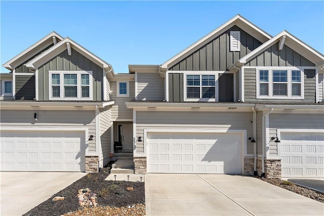 view of front of home with stone siding, board and batten siding, an attached garage, and concrete driveway