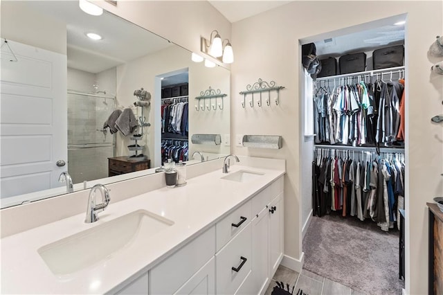 bathroom with double vanity, a shower stall, a spacious closet, and a sink