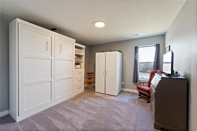 bedroom featuring baseboards, light carpet, a textured ceiling, and visible vents