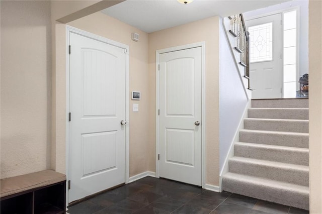 entrance foyer featuring stairway and baseboards