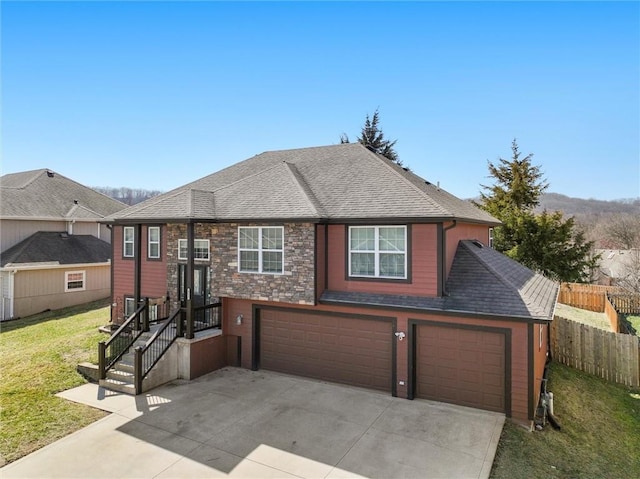 view of front of house with a front lawn, fence, roof with shingles, concrete driveway, and a garage