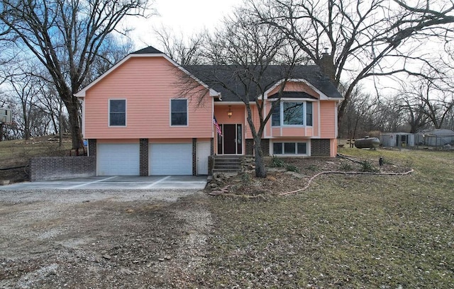 split foyer home featuring a garage, brick siding, and driveway