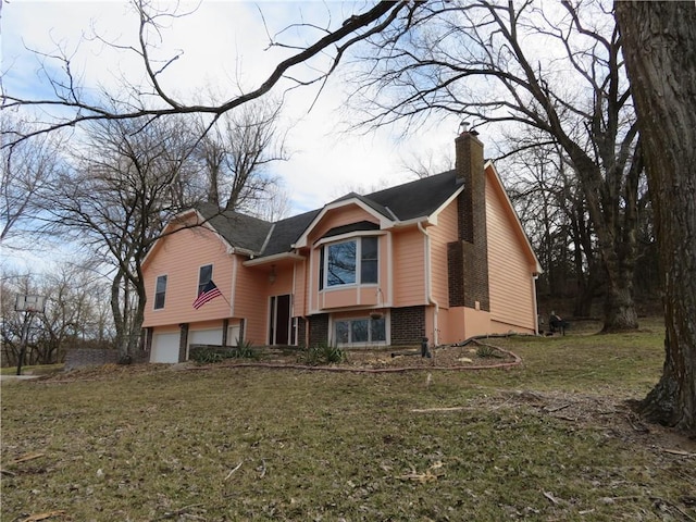 split foyer home with a garage, a front yard, brick siding, and a chimney